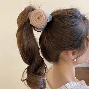 Détail de la pince à cheveux rose en tissu avec nœud sur une coiffure queue de cheval
