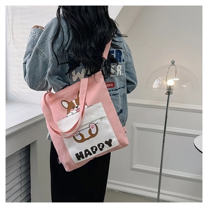 Detail of pink canvas tote bag with corgi puppy print worn by model in casual setting
