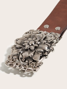 Close-up of vintage floral embossed silver buckle on a premium brown leather punk belt