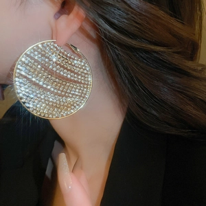 Close-up of pavé crystal large gold hoop earrings on a model with premium lighting