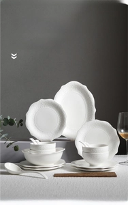 Detail showing white relief ceramic dinnerware set with elegant embossed lace patterns
