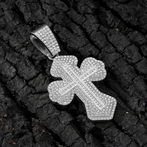 Macro shot of a silver hip hop cross pendant with iced-out rhinestones on charcoal