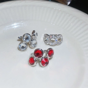 Close-up of geometric zirconia rings in silver and red stones on a white ceramic plate