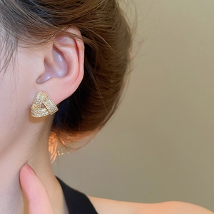 Close-up of elegant gold triangle stud earrings with sparkling cubic zirconia on model