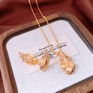 Detailed close-up of 18k gold-plated feather jewelry set with sparkling pavé stones