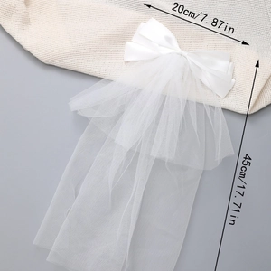 White tulle bow hair clip with long ribbons 45cm length shown on textured fabric