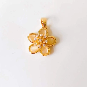 Detailed close-up of 18k gold flower pendant with opal petals and crystal center