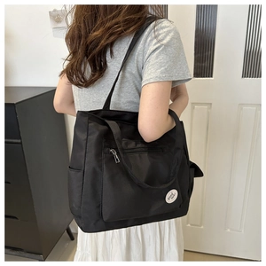 Side view of a large black nylon tote bag on shoulder showing its spacious capacity