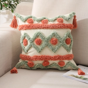 Macro detail of tufted geometric patterns and tassels on a beige cotton-linen pillow cover