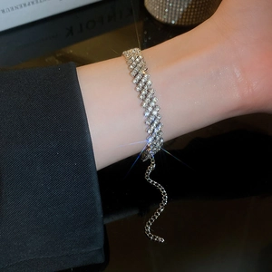 Bracelet géométrique argenté avec cristaux de luxe sur poignet avec fond noir et effet brillant