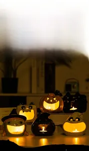 Macro shot of Halloween ceramic pumpkin and ghost candle holders with glowing cut-out eyes