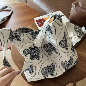 Detail view of cream canvas tote bag featuring a vintage butterfly print on a wooden table