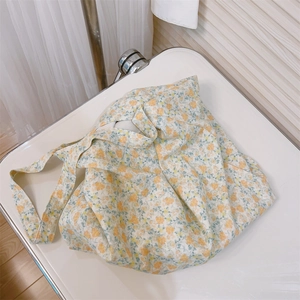 Detailed close-up of a floral cotton tote bag featuring small yellow and orange blossoms