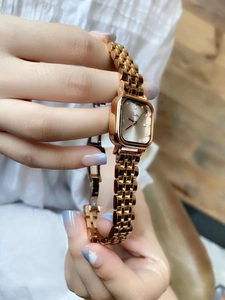 Close-up of rose gold square quartz watch with diamond markers and sleek metal strap