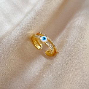 Macro detail of gold plated evil eye ring with white zircon on silk fabric