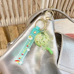 Quicksand bottle keychain with green lollipop pendant on a shiny silver bag