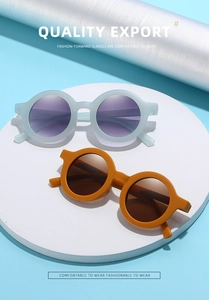 Close-up of matte ginger yellow and light blue kids sunglasses on a white round platform