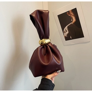 Detail of burgundy leather bucket bag with oversized gold metal buckle and pleated design