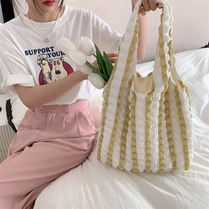 Detail of yellow and white striped bubble fabric tote bag on a white bedding backdrop