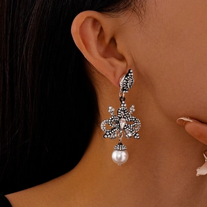 Close-up of vintage black bow earrings with rhinestones and a large white pearl drop