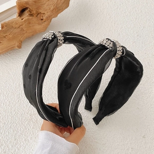 Detail of black silk knot headbands with embroidered hearts and sparkling diamond buckle