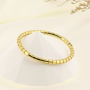 Detailed view of an 18K gold plated bamboo link bangle on a minimalist display stand