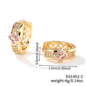 Detail of gold huggie earrings featuring pink four-leaf flowers and white zircon stones