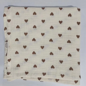 Detail of double-layer muslin baby swaddle featuring brown heart prints and soft texture