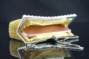 Detail der goldenen Perlen-Abendtasche mit gelbem Futter und silbernem Kettenriemen