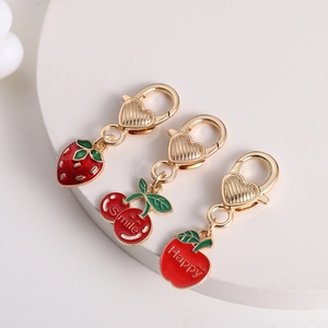 Detail of gold zinc alloy charms featuring strawberry, cherry, and apple fruit pendants