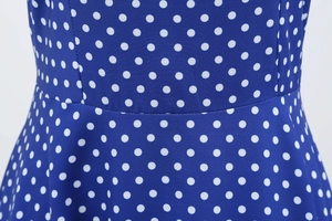 Detailed close-up of the waist stitching on this blue polka dot dress with woven fabric