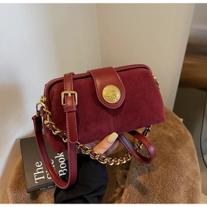 Detail of burgundy doctor bag featuring matte leather texture and gold animal relief buckle