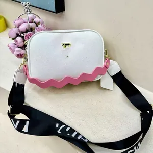 White pebbled leather crossbody camera bag with pink wavy handle and logo strap