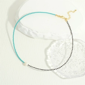 Detail of bohemian necklace with turquoise and black glass beads and freshwater pearl
