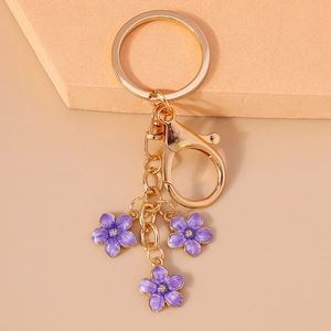 Detail of a gold keychain featuring three purple enamel cherry blossom flower pendants