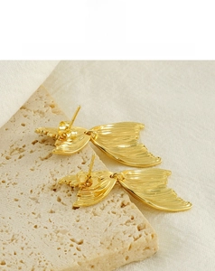 Détail de boucles d'oreilles queue de poisson 18K avec texture en métal brossé