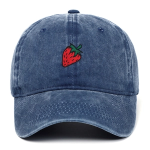 Close-up detail of strawberry embroidery on vintage washed blue denim baseball cap