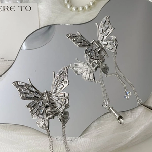 Detailed view of silver butterfly hair clips with shimmering crystals and long tassels