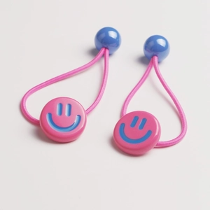 Detailed view of pink elastic hair ties with blue smiley face and spherical bead accents