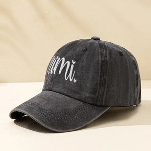 Close-up of white Mimi embroidery and heart detail on washed dark grey cotton baseball cap