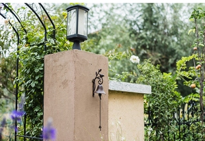Close-up of vintage cast iron garden doorbell with bird ornament on a stone pillar