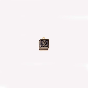 Macro shot of a black enamel gothic spell book pendant with golden pentagram detail