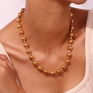 Gros plan d'un collier de perles dorees sur un modele montrant l'eclat poli