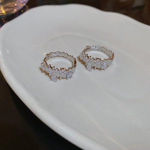 Macro shot of silver zircon hoop earrings on white textured ceramic jewelry dish