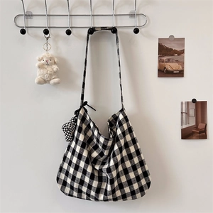 Detail of checkered canvas tote bag with matching heart pendant on a metal hook