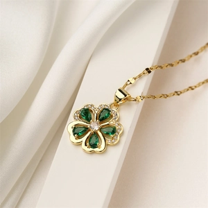 Macro shot of gold clover pendant with green pear-shaped gems and crystal center