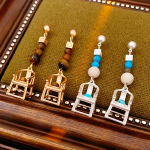 Close-up of vintage chair drop earrings with colorful beads on brown velvet