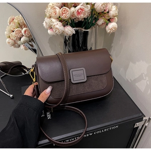 Detailed view of dark brown leather crossbody bag with metallic logo clasp and matte finish