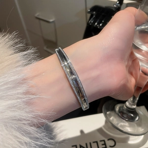 Detailed view of silver cuff bracelet with micro-pave zircons and relief emblem