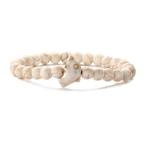 Macro detail of white turquoise beaded bracelet with a silver dolphin charm and marble texture